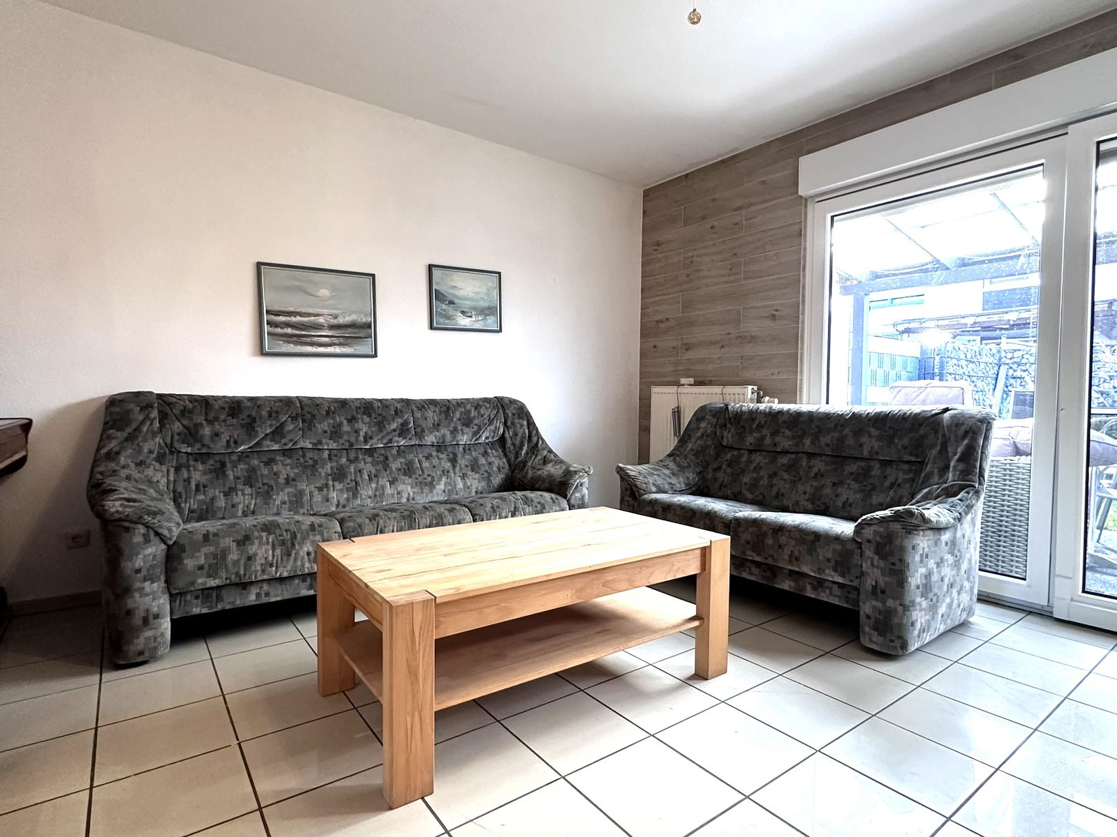 Gemütlicher Aufenthaltsraum im Monteurhaus Elsenfeld mit zwei Sofas und Terrassenzugang